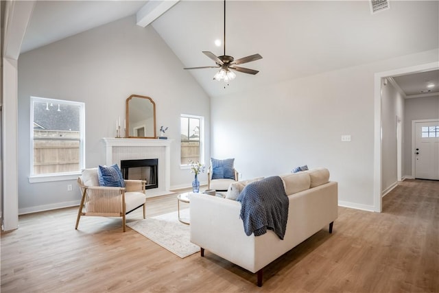 living room with ceiling fan, light hardwood / wood-style flooring, high vaulted ceiling, and beamed ceiling