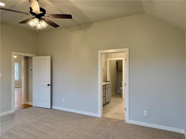 unfurnished bedroom with ensuite bath, light colored carpet, vaulted ceiling, and ceiling fan