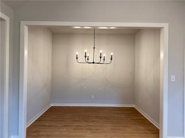 unfurnished dining area featuring a notable chandelier and wood-type flooring