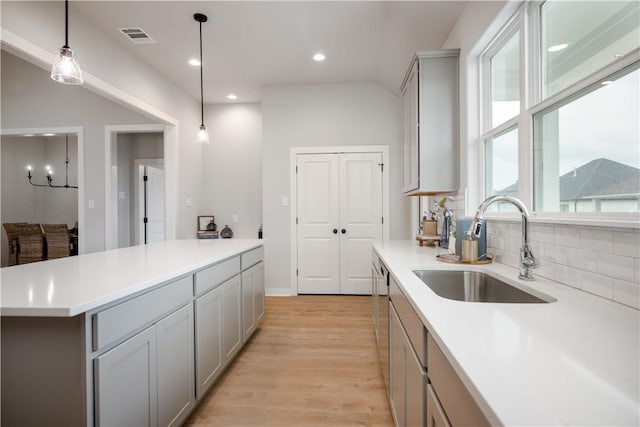 kitchen featuring pendant lighting, sink, gray cabinetry, light hardwood / wood-style floors, and a kitchen island