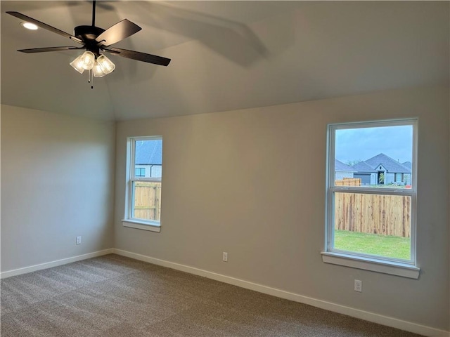 carpeted spare room with ceiling fan and vaulted ceiling