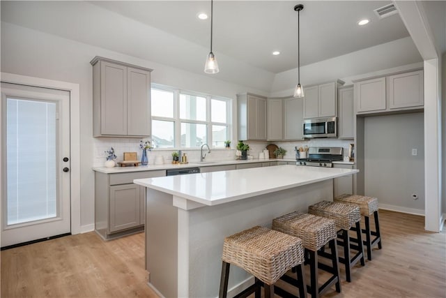 kitchen featuring sink, appliances with stainless steel finishes, a kitchen breakfast bar, a center island, and decorative backsplash