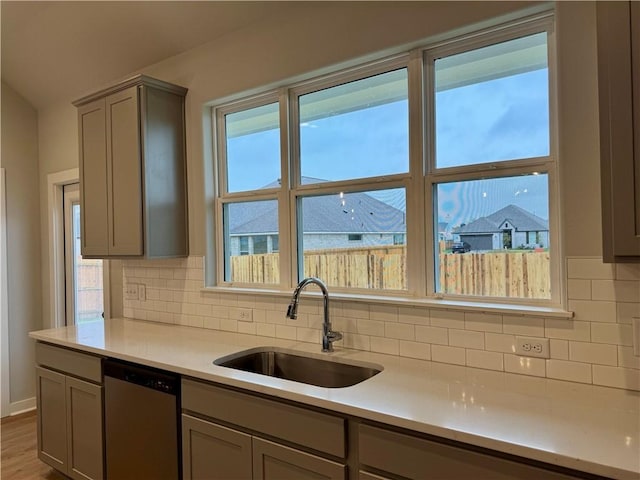 kitchen featuring backsplash, sink, hardwood / wood-style flooring, dishwasher, and gray cabinets