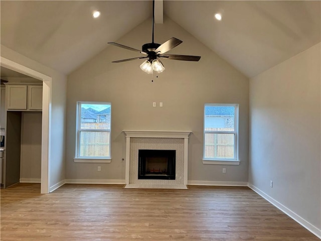 unfurnished living room with a wealth of natural light, ceiling fan, light hardwood / wood-style flooring, and lofted ceiling with beams