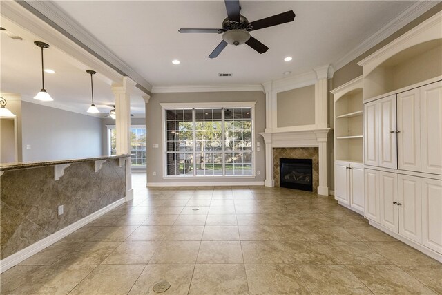 unfurnished living room with a fireplace, ceiling fan, built in features, and crown molding