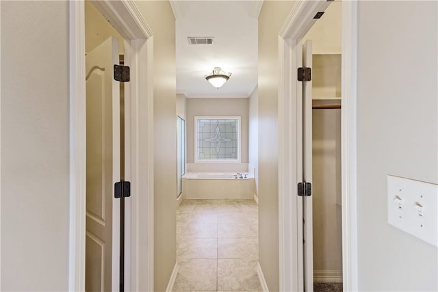 corridor featuring light tile patterned floors and crown molding