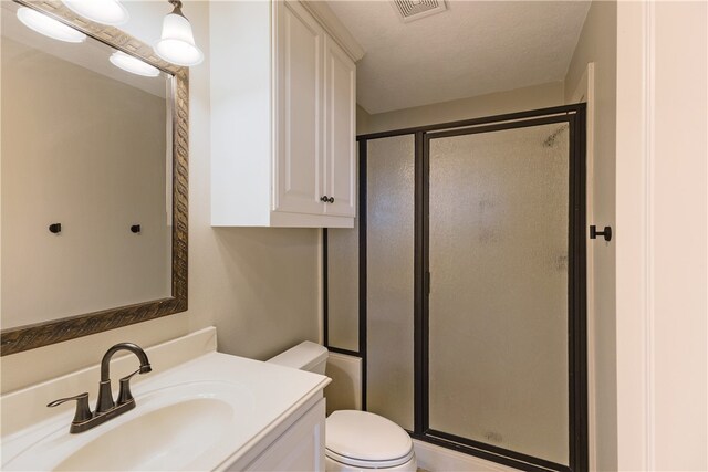 bathroom featuring toilet, vanity, a textured ceiling, and walk in shower