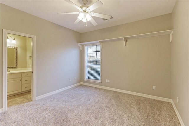 unfurnished bedroom with connected bathroom, light colored carpet, and ceiling fan