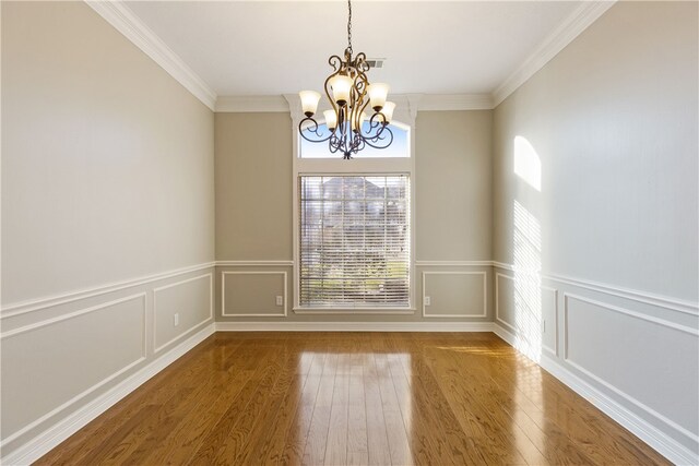 unfurnished room with ornamental molding, a chandelier, and hardwood / wood-style flooring