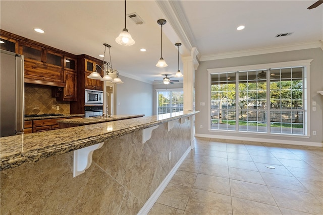 kitchen with light stone countertops, ceiling fan, decorative light fixtures, a kitchen bar, and ornamental molding