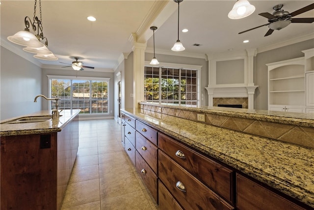 kitchen featuring pendant lighting, ornamental molding, sink, and light tile patterned floors