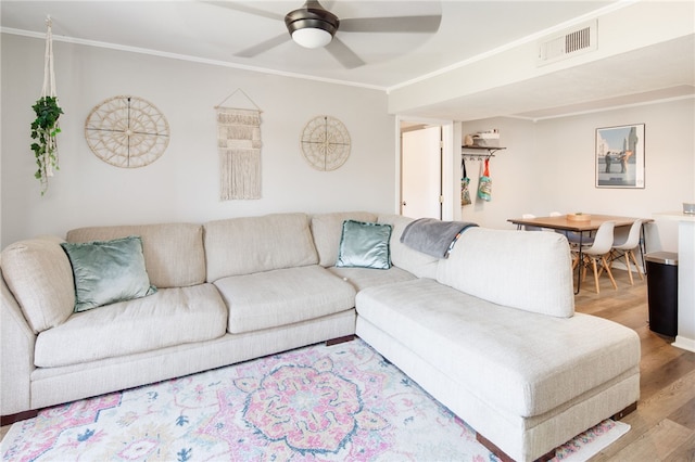 living room with visible vents, ornamental molding, a ceiling fan, and wood finished floors