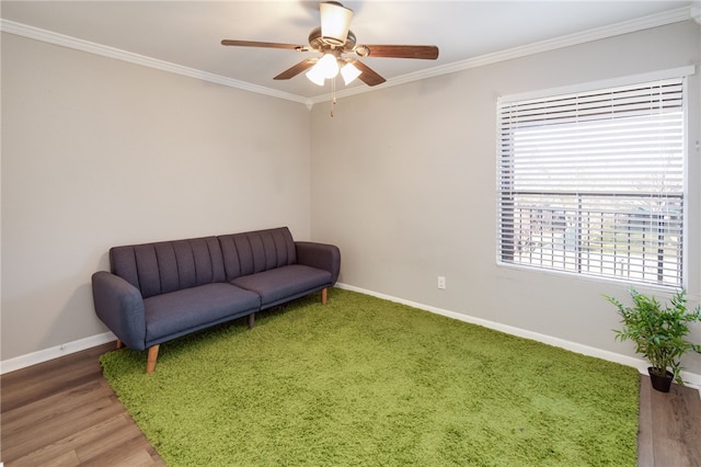 sitting room with ceiling fan, wood finished floors, baseboards, and ornamental molding