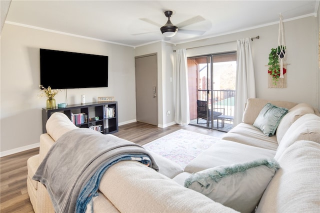 living area with baseboards, wood finished floors, and ornamental molding