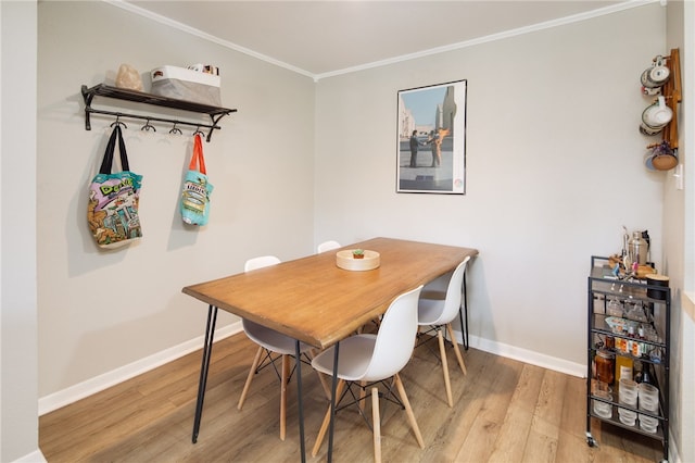 dining space featuring light wood-style flooring, crown molding, and baseboards