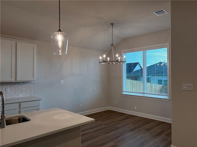 kitchen with pendant lighting, backsplash, vaulted ceiling, and sink