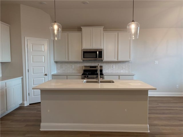 kitchen featuring decorative light fixtures, stainless steel appliances, and a center island with sink