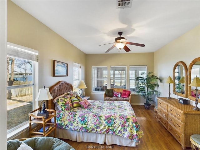 bedroom with ceiling fan, dark hardwood / wood-style flooring, and multiple windows