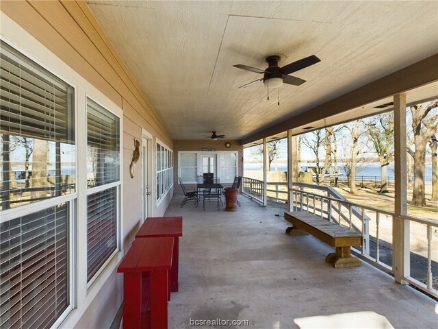 unfurnished sunroom with ceiling fan and a water view