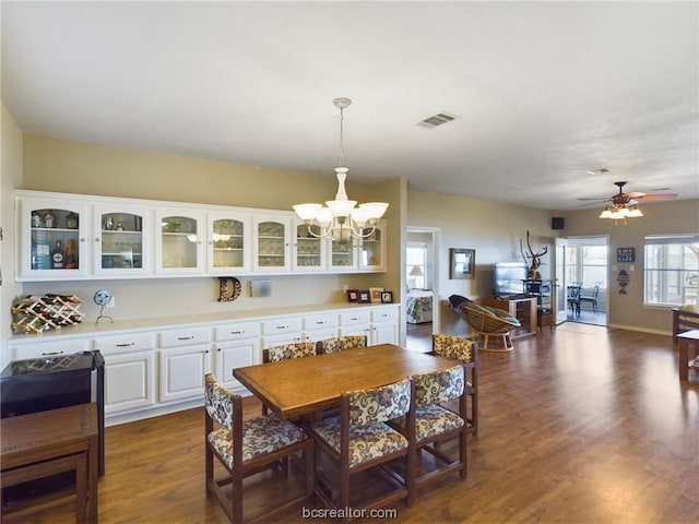 dining space featuring dark wood-type flooring and ceiling fan with notable chandelier