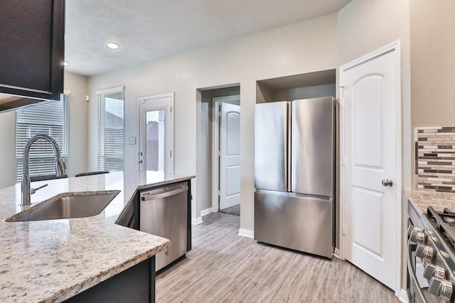 107 Meadow Lake Ct, Navasota, TX 77868 - kitchen with stainless steel appliances, a sink, light stone counters, light wood finished floors, and recessed lighting