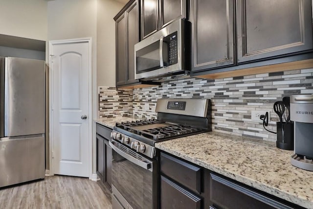 107 Meadow Lake Ct, Navasota, TX 77868 - kitchen with stainless steel appliances, light stone counters, decorative backsplash, and light wood-type flooring