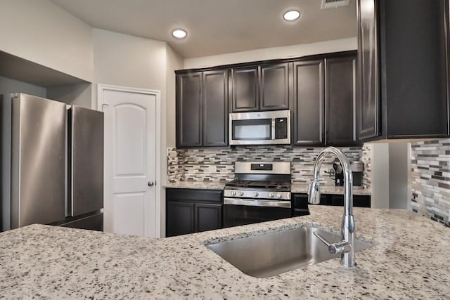 107 Meadow Lake Ct, Navasota, TX 77868 - kitchen with appliances with stainless steel finishes, a sink, light stone counters, decorative backsplash, and recessed lighting