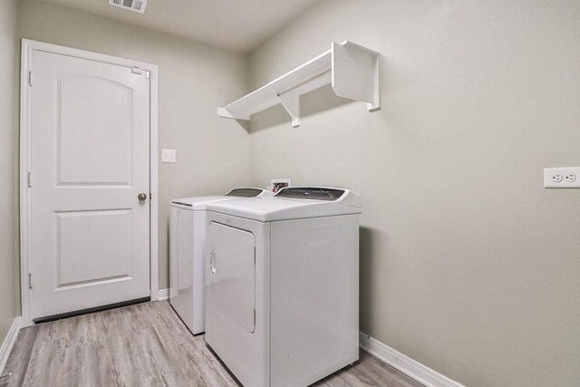 107 Meadow Lake Ct, Navasota, TX 77868 - laundry area featuring washing machine and clothes dryer, light wood-style flooring, and baseboards
