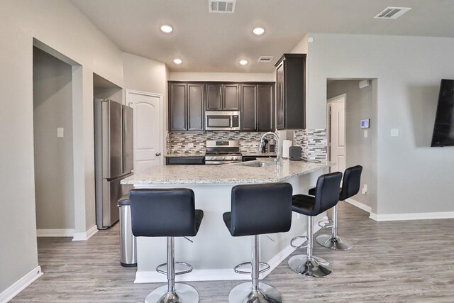 107 Meadow Lake Ct, Navasota, TX 77868 - kitchen with stainless steel appliances, baseboards, light wood-style floors, a breakfast bar area, and tasteful backsplash