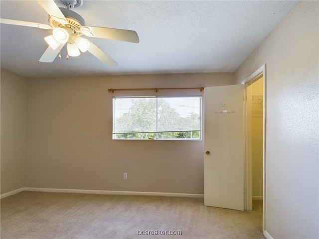 empty room with ceiling fan, light colored carpet, and a textured ceiling