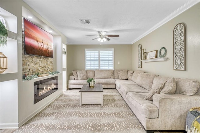 living area with ornamental molding, visible vents, ceiling fan, baseboards, and a glass covered fireplace