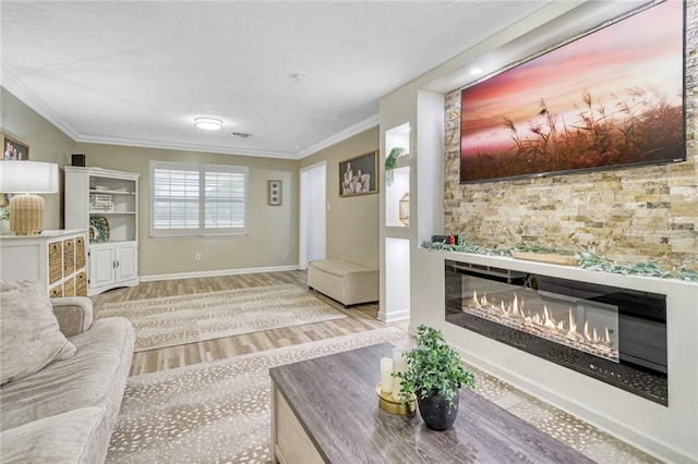 living room with baseboards, ornamental molding, a glass covered fireplace, and wood finished floors
