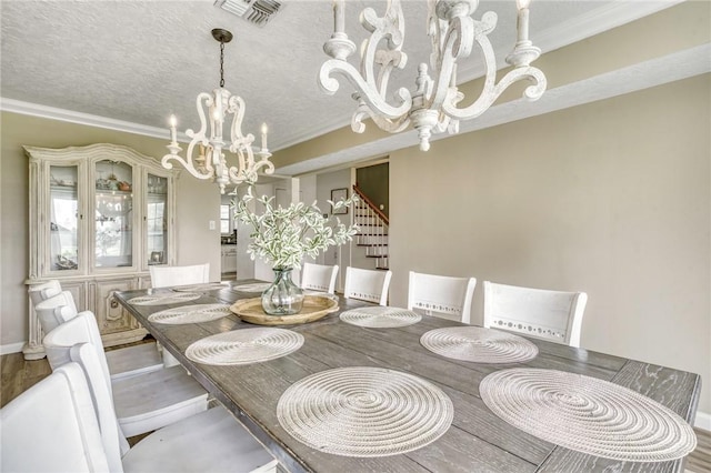 dining room featuring a chandelier, ornamental molding, visible vents, and wood finished floors