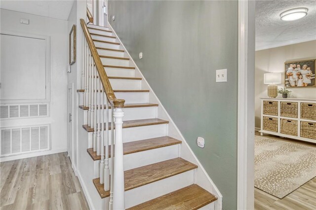 stairway featuring a textured ceiling, visible vents, and wood finished floors