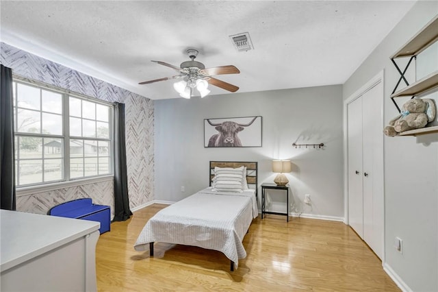 bedroom with baseboards, light wood finished floors, and visible vents
