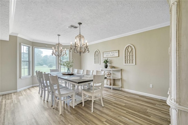 dining room featuring a notable chandelier, baseboards, ornamental molding, visible vents, and light wood-type flooring