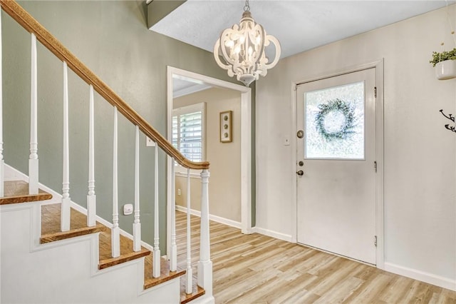 entryway with a chandelier, stairs, a wealth of natural light, and wood finished floors
