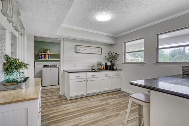 kitchen featuring light wood-style flooring, stainless steel appliances, a peninsula, and a textured ceiling