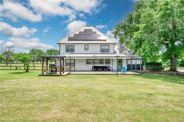 back of property featuring a yard, outdoor lounge area, fence, a patio, and solar panels