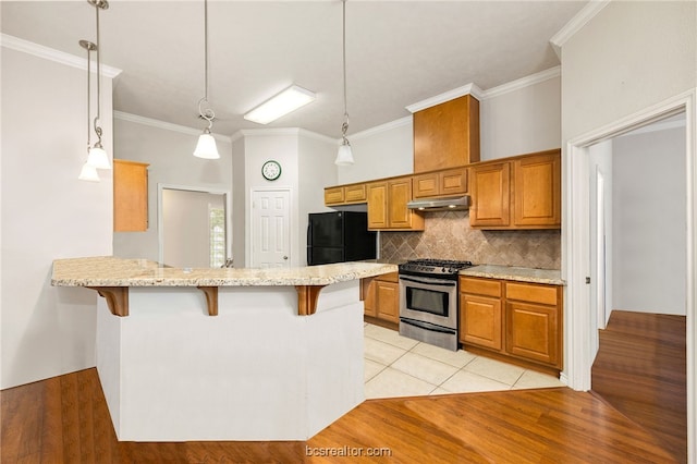 934 Dove Landing Ave, College Station, TX 77845 - kitchen with a breakfast bar area, freestanding refrigerator, under cabinet range hood, and stainless steel range with gas cooktop