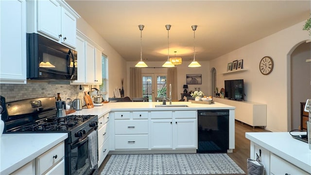 301 Pine Mist Ln, Conroe, TX 77304 - kitchen featuring arched walkways, black appliances, a peninsula, light countertops, and backsplash