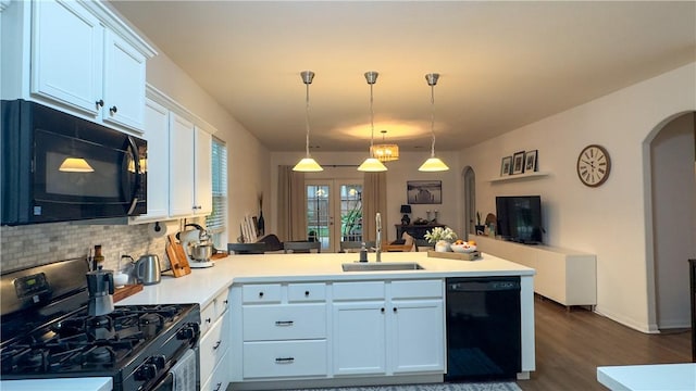 301 Pine Mist Ln, Conroe, TX 77304 - kitchen with arched walkways, black appliances, a peninsula, tasteful backsplash, and dark wood-style flooring