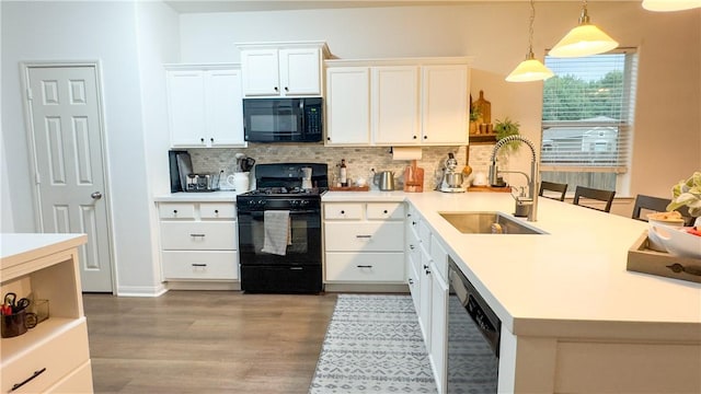 301 Pine Mist Ln, Conroe, TX 77304 - kitchen featuring black appliances, a peninsula, tasteful backsplash, light wood finished floors, and white cabinetry