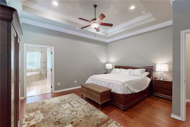 bedroom featuring ensuite bathroom, ornamental molding, dark hardwood / wood-style floors, and a raised ceiling