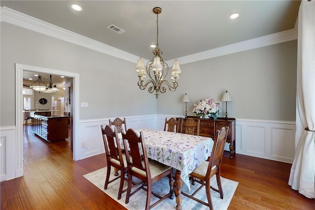 dining room with crown molding, a chandelier, and hardwood / wood-style floors