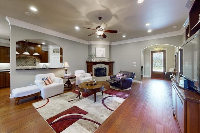 living room featuring sink, light hardwood / wood-style flooring, ornamental molding, and ceiling fan