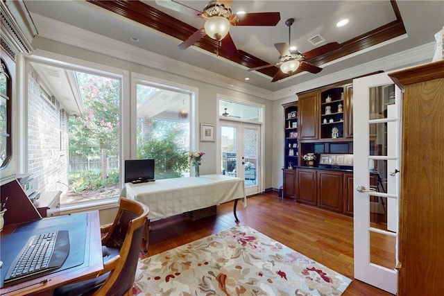 office space featuring a raised ceiling, ornamental molding, hardwood / wood-style flooring, and french doors