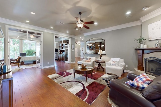 living room featuring hardwood / wood-style flooring, ceiling fan, and ornamental molding