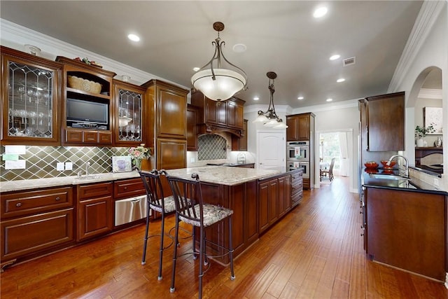 kitchen with sink, hanging light fixtures, light stone countertops, a kitchen island, and dark hardwood / wood-style flooring