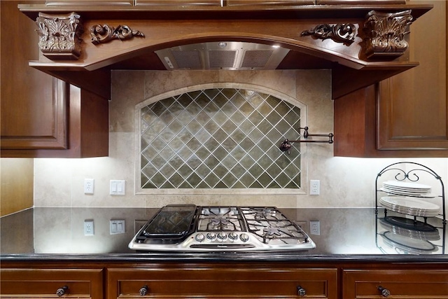 kitchen with custom exhaust hood, stainless steel gas cooktop, and decorative backsplash